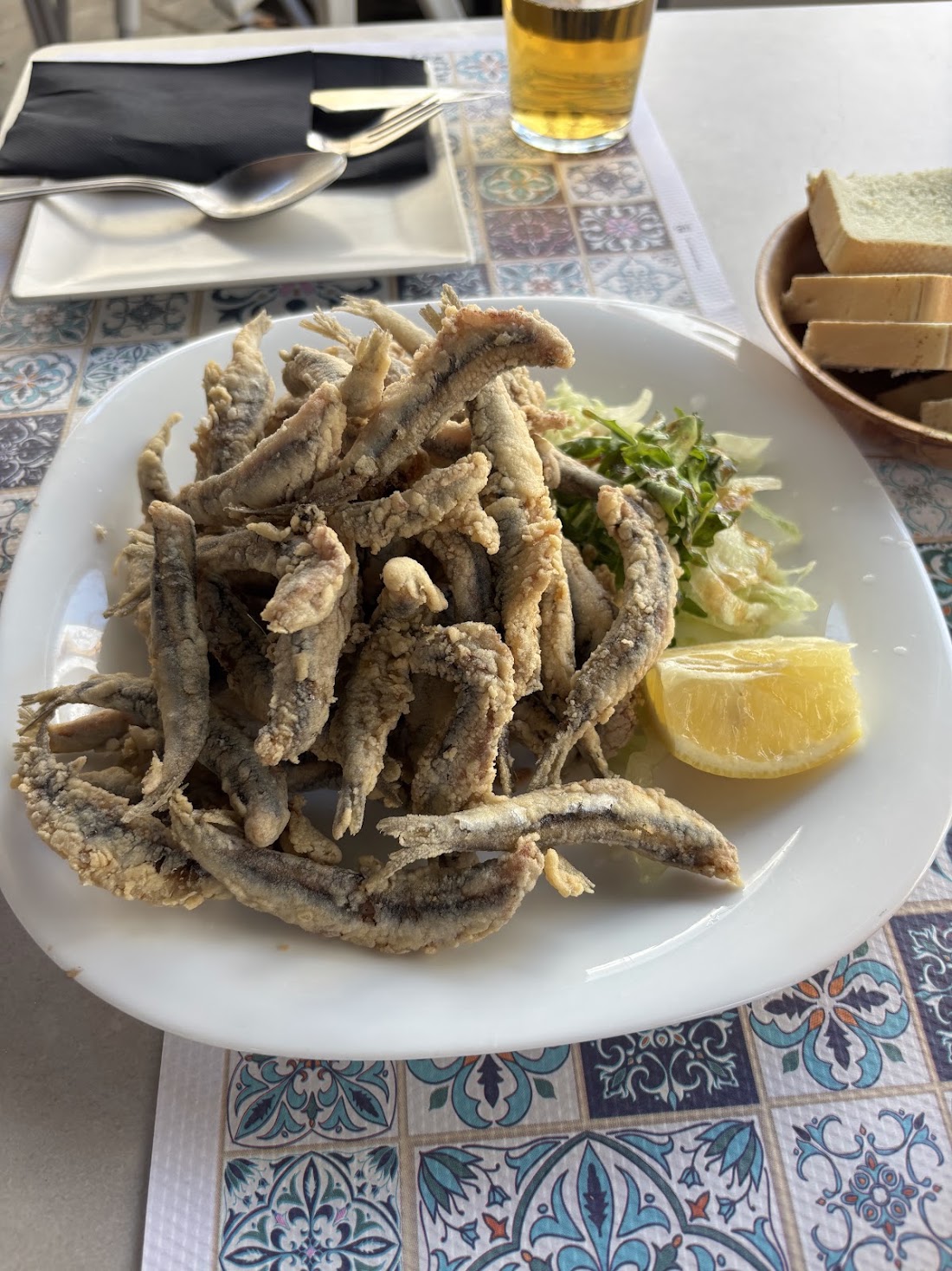 Boquerones fritos con limón sobre mantel de azulejos