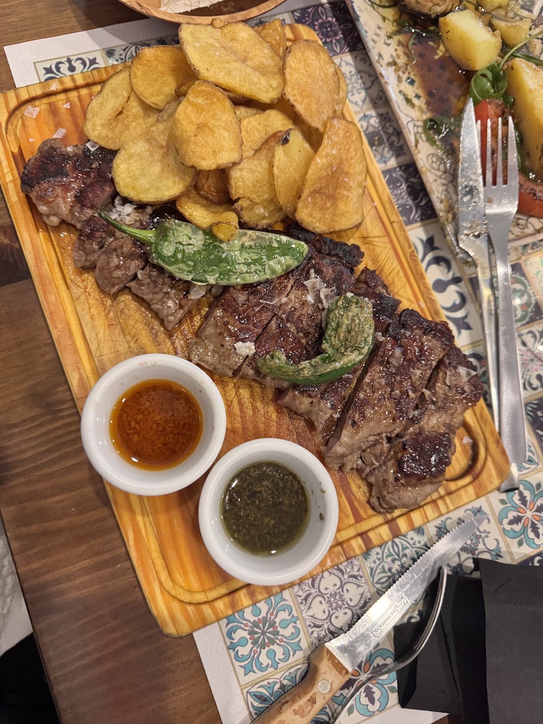 Carne a la brasa en tabla con patatas y dos salsas