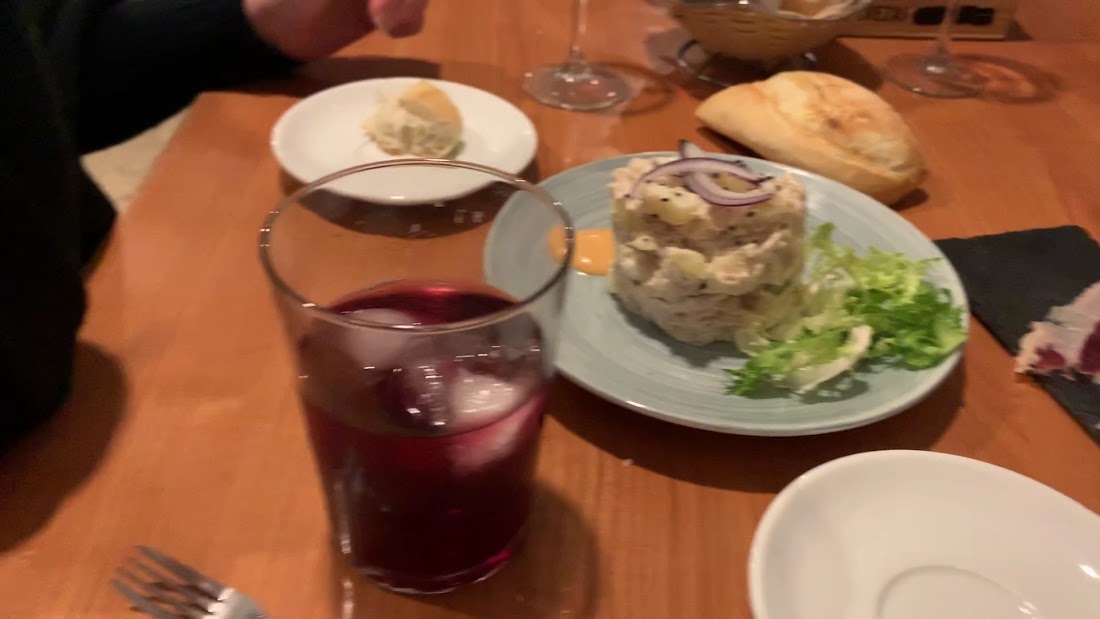 Vaso de sangría junto a un plato de ensaladilla y pan