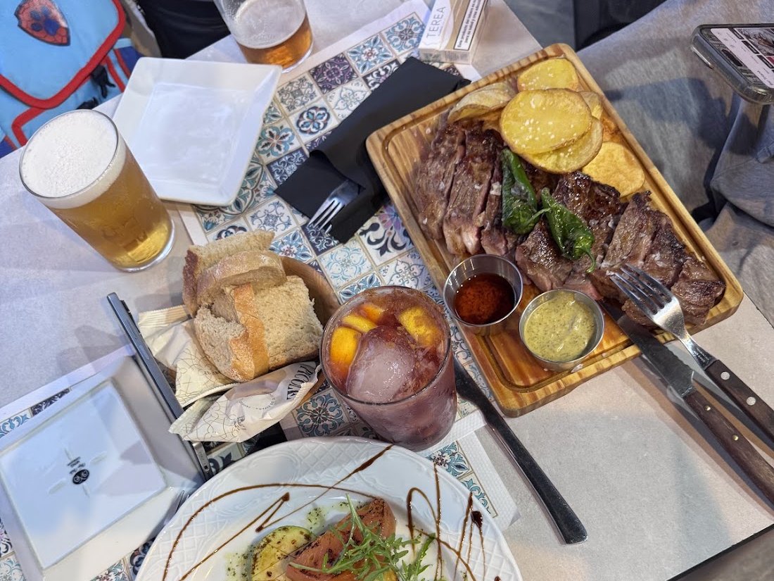 Mesa de la terraza con carne a la brasa, atún con verduras, sangría y cerveza